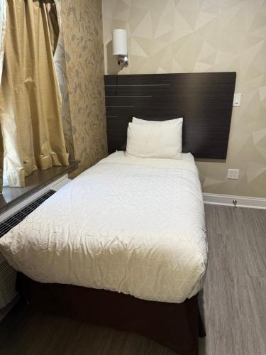 a bedroom with a bed with white sheets and pillows at Grandview Hotel New York in Queens