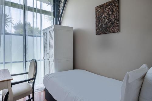 a white bedroom with a bed and a window at La Villa Mauresque in Saint-Raphaël