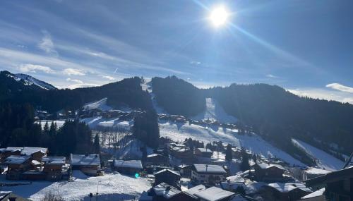 un pueblo cubierto de nieve con el sol en el cielo en Le Gibannaz, en Les Gets