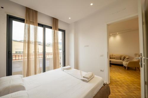 a bedroom with a bed and a large window at Tirent Apartment-Modern Bedrooms Stay Near Liqeni i Thatë in Tirana