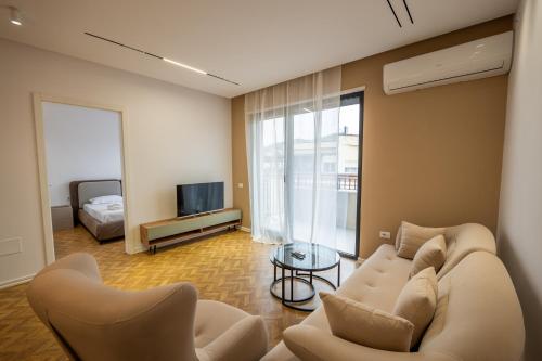 a living room with a couch and a tv at Tirent Apartment-Modern Bedrooms Stay Near Liqeni i Thatë in Tirana