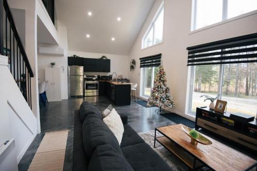 a living room with a couch and a christmas tree at Chalet Escapade, Spa, Piscine in La Patrie