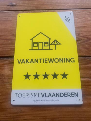 a yellow warning sign on a wooden table at Maison Remy in Ypres