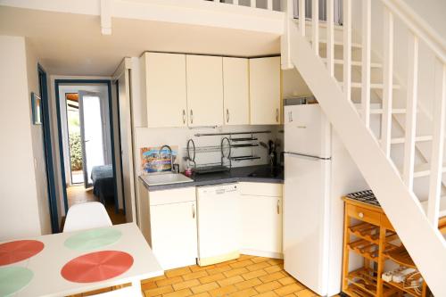 une cuisine avec des placards blancs et un escalier en colimaçon dans l'établissement Saint Cyprien jolie maison climatisee, à Saint-Cyprien