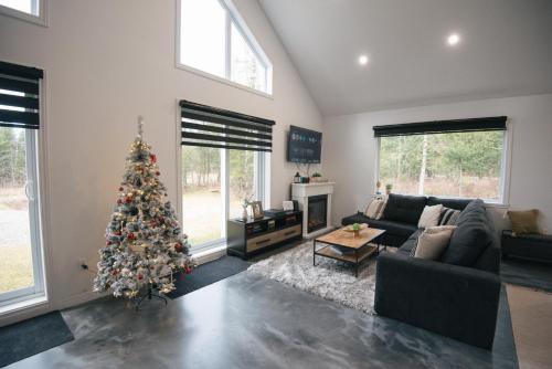 a living room with a christmas tree in it at Chalet Escapade, Spa, Piscine in La Patrie