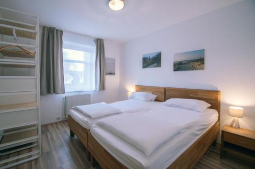 a bedroom with a large white bed and a window at Strandhus 1 in Borkum