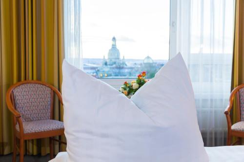 a pillow sitting on a bed in a room with a window at Hotel Am Terrassenufer in Dresden