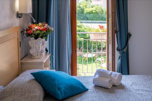 a bedroom with a bed with a blue pillow and a window at Hotel Baia Del Capitano in Cefalù
