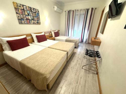 a hotel room with two beds and a tv at Paradouro in Lisbon