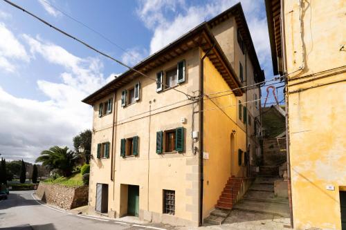 a yellow building with green windows on a street at Lajatico Rentals -Grotticella House, SPA Apartment in Peccioli in Peccioli