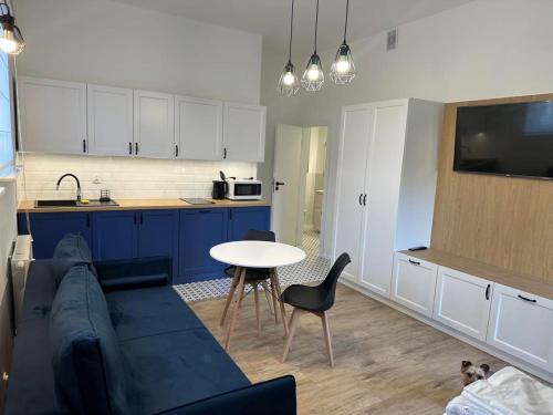 a living room with a couch and a table and a kitchen at Apartament Cicha 3 Sztutowo in Sztutowo