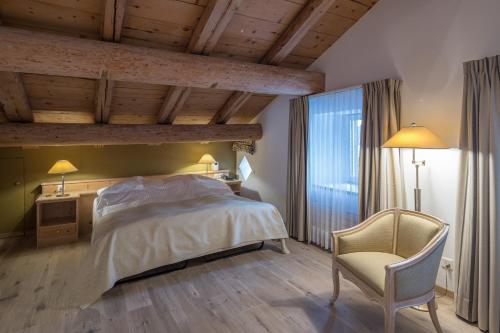 a bedroom with a bed and a chair at Hotel Post in Bivio