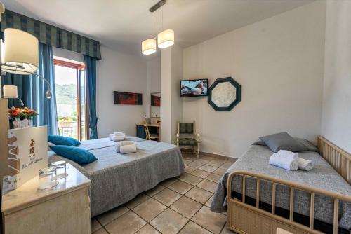 a bedroom with two beds and a window at Hotel Baia Del Capitano in Cefalù