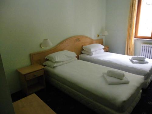 two beds in a hotel room with two towels at Hotel Residence Valverde in Gressoney-la-Trinité