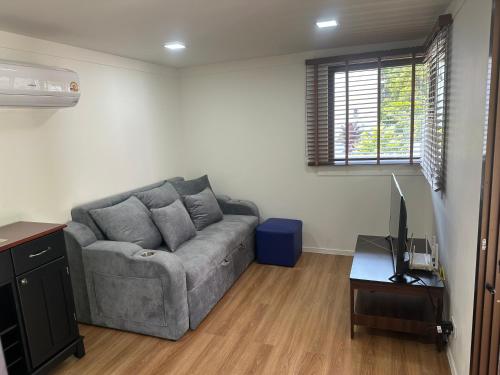 a living room with a gray couch and a television at The Aura Pranburi in Ban Tha Khoi