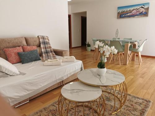 ein Wohnzimmer mit einem Sofa und einem Tisch mit Blumen darauf in der Unterkunft Pico Barcelos - Funchal in Funchal