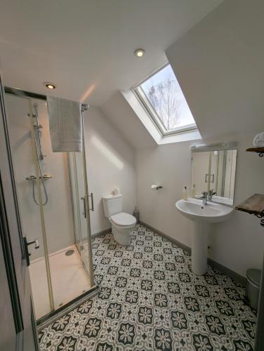 a bathroom with a shower and a sink and a toilet at Jacobite Lodge by The House of Danu in Kingussie