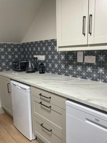 a kitchen with white cabinets and a counter top at Gills Courtyard Accommodation in Crossmolina