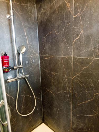 La salle de bains est pourvue d'une douche et d'un mur en marbre noir. dans l'établissement Bel appartement proche gare et centre ville, au Mans