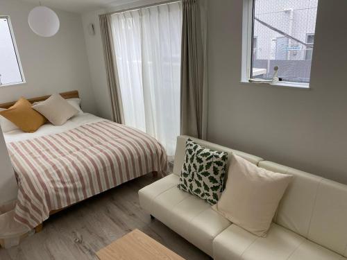 a bedroom with a bed and a couch and a window at Y's INN Nakai 005T in Tokyo