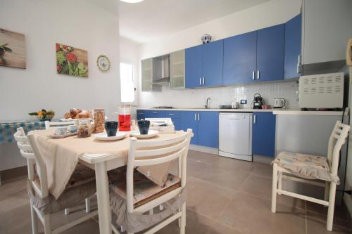 a kitchen with blue cabinets and a table and chairs at VILLA CALA BERNARDO 2 Appartamenti in Calabernardo