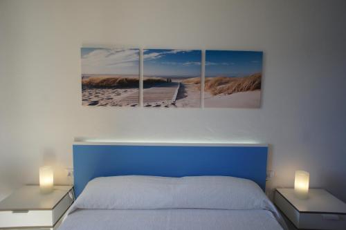 a bedroom with a blue bed and three paintings on the wall at Nuvolet Apartaments in Cala en Blanes