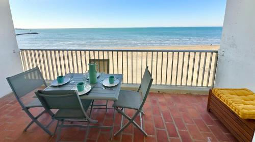 une table et des chaises sur un balcon avec vue sur la plage dans l'établissement L'Océanide face à la mer, au Grau-du-Roi