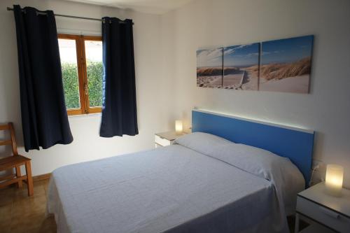 a bedroom with a blue bed and a window at Nuvolet Apartaments in Cala en Blanes