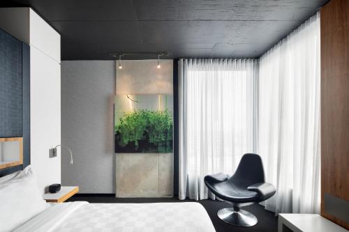 a bedroom with a chair and a bed and a window at Alt Hotel Toronto Airport in Mississauga