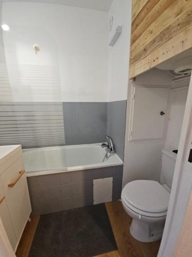 une salle de bain avec une baignoire blanche et des toilettes dans l'établissement Studio au pied des pistes refait à neuf, à Enchastrayes