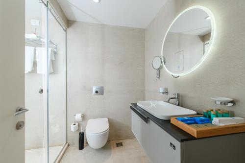 a white bathroom with a sink and a mirror at Folie Marine Hotel & Beach Club in Jal