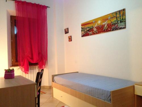 a bedroom with a bed and a desk and a red curtain at Borgo Rosia Holiday House in Rosia