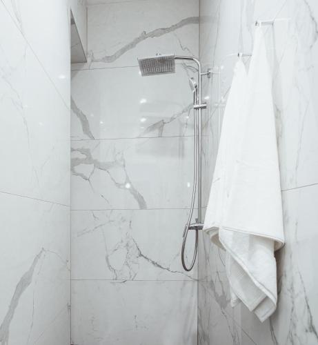 a bathroom with a shower with white marble walls at Royal Central Apartments in Zagreb