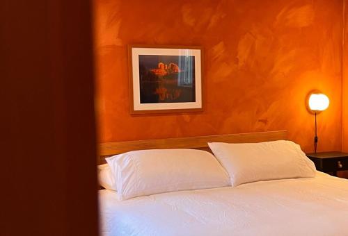a bed with two pillows and a picture on the wall at Sunshine House - Nestled In Page Springs in Cottonwood