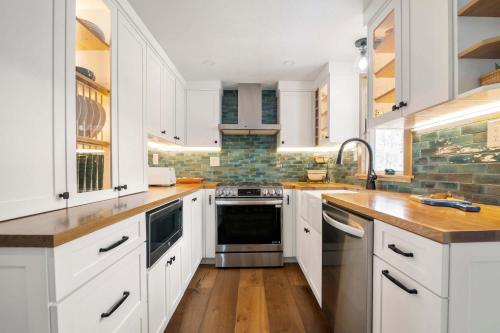 a white kitchen with wooden floors and white cabinets at Sunroom Central A C Large Fenced Yard in Yarmouth