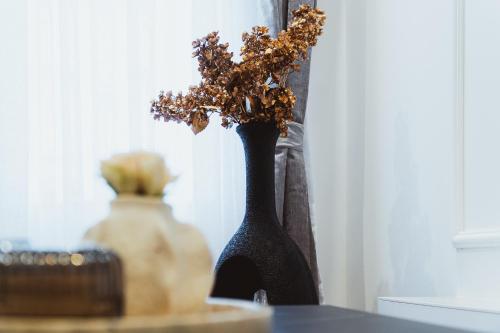 a black vase with flowers in it on a table at Royal Central Apartments in Zagreb