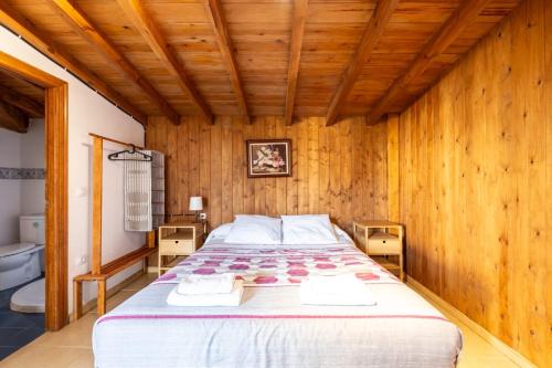 ein Schlafzimmer mit einem großen Bett an einer Holzwand in der Unterkunft Casa Villa Maria in Canales