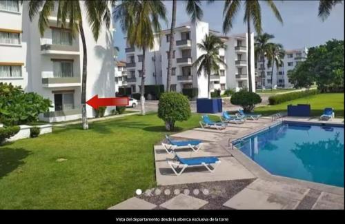 a swimming pool with lounge chairs and a large building at Padrisimo Departamento p6 personas en planta baja in Manzanillo