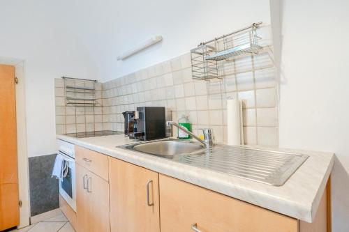 a kitchen with a sink and a tiled wall at Whats-App Self-Check-IN - Bad Aussee City House in Bad Aussee