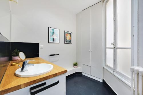 une salle de bain blanche avec un lavabo et un miroir dans l'établissement Spacieux 2P à Paris, rue Jouffroy d'Abbans proche Arc de Triomphe, à Paris