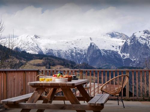 - une table avec un bol de fruits sur une terrasse avec des montagnes dans l'établissement Chalet Morclan - OVO Network, à Manigod