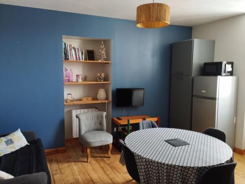 un salon avec une table et un mur bleu dans l'établissement Appartement de charme à la montagne, à Ax-les-Thermes