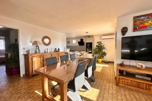 une salle à manger avec une table et une télévision dans l'établissement L'Olivier, au Grau-du-Roi