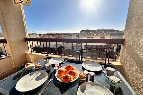 une table avec deux assiettes de nourriture sur un balcon dans l'établissement L'Olivier, au Grau-du-Roi