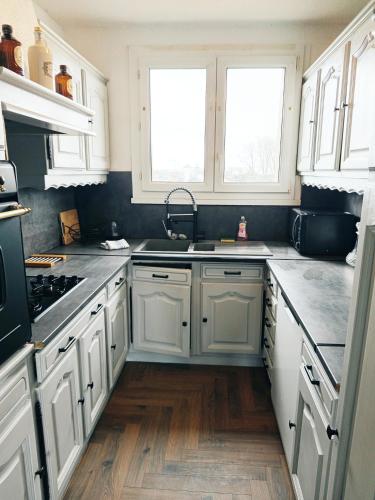 - une cuisine avec des placards blancs, un évier et 2 fenêtres dans l'établissement Bel appartement proche gare et centre ville, au Mans