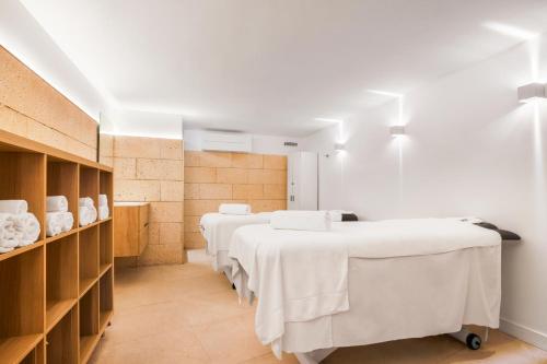 a row of beds in a room with white sheets at Aparthotel Fontanellas Playa in Playa de Palma