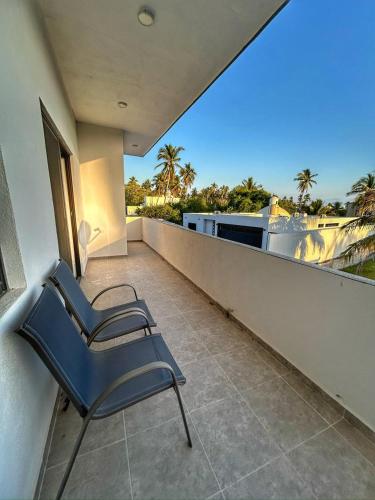 two chairs sitting on the balcony of a house at Apolo Apartment, near the beach with pool in Barra de Navidad