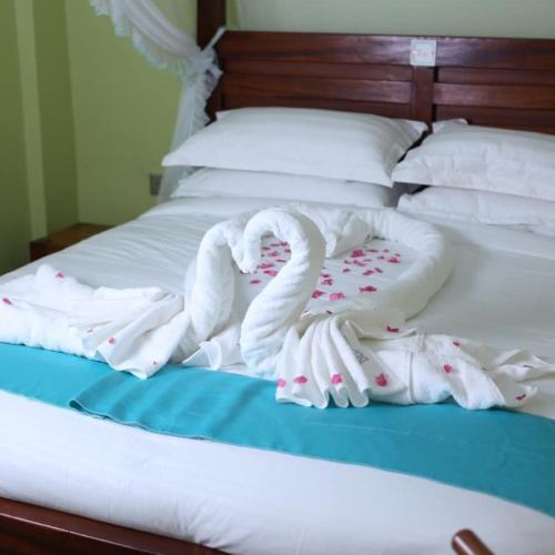 a bed with white blankets and pillows on it at Bedarin Hotel Limited in Ruiru