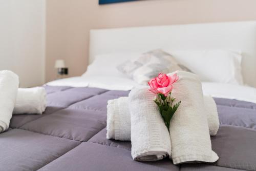 a pink rose sitting on top of a bed at Luxury 12 in Tuglie