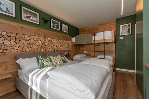 2 camas en una habitación con paredes verdes y madera en Casa Te Volto, en Moena